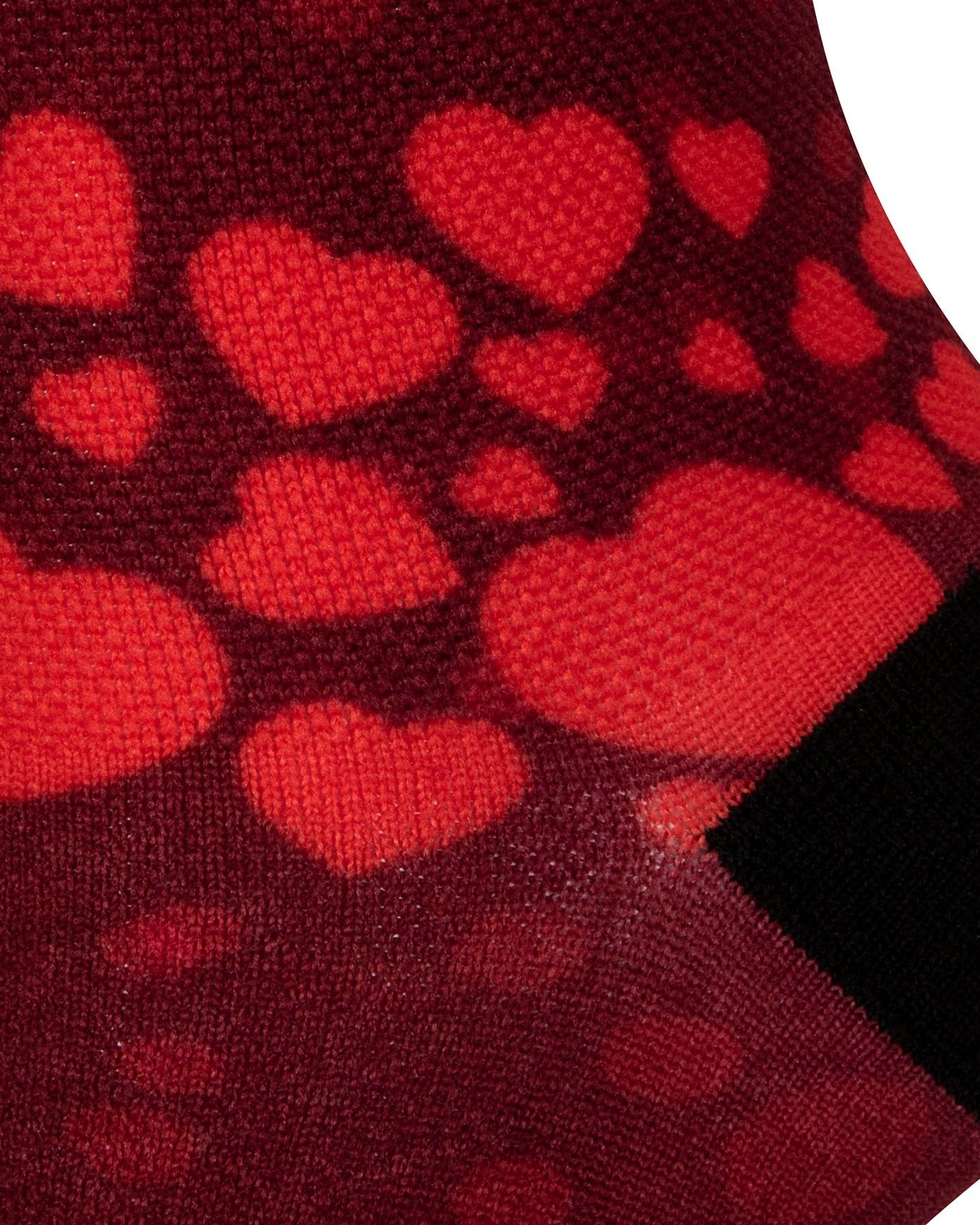 Textured heel view of a red seamless toe sock with red hearts print design and black heel.