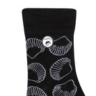 Side view of a combed cotton black seamless toe anklet with white outlined sea shells with Dapper Chameleon logo.