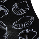 Textured view of a combed cotton black seamless toe anklet with white outlined sea shells.